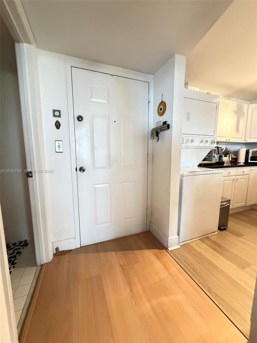 A white front door opens into a room with light wood flooring and a kitchen — 540 Brickell Key Dr # 828, Miami FL 33131, MIAMI, FL