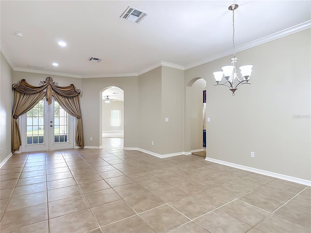 A dining area with tile flooring, a chandelier, and French doors with decorative curtains — 3603 DAYDREAM PLACE, ST CLOUD, FL