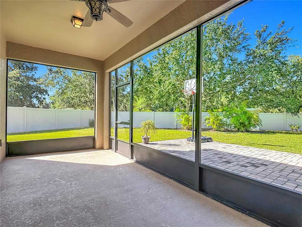 A screened-in patio with a concrete floor, ceiling fan, and view of a backyard — 3603 DAYDREAM PLACE, ST CLOUD, FL