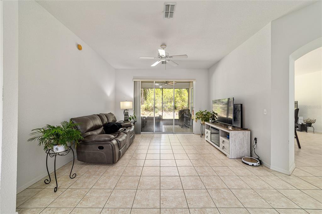 A living room with tile flooring, a gray sofa, a television console, and sliding glass doors — 20870 SW 90TH LOOP, DUNNELLON, FL