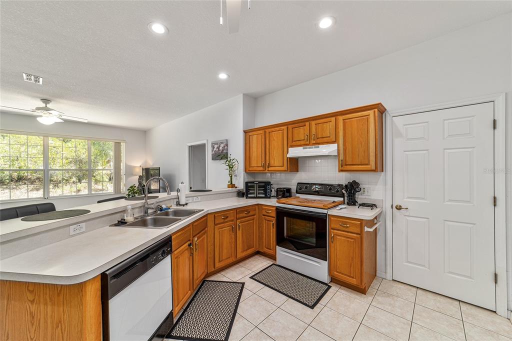 A kitchen features wood cabinets, white countertops, a double sink, and tile flooring — 20870 SW 90TH LOOP, DUNNELLON, FL