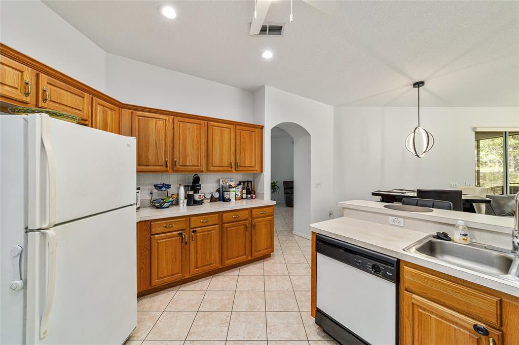 A kitchen features wood cabinets, white appliances, tile flooring, and a breakfast bar — 20870 SW 90TH LOOP, DUNNELLON, FL