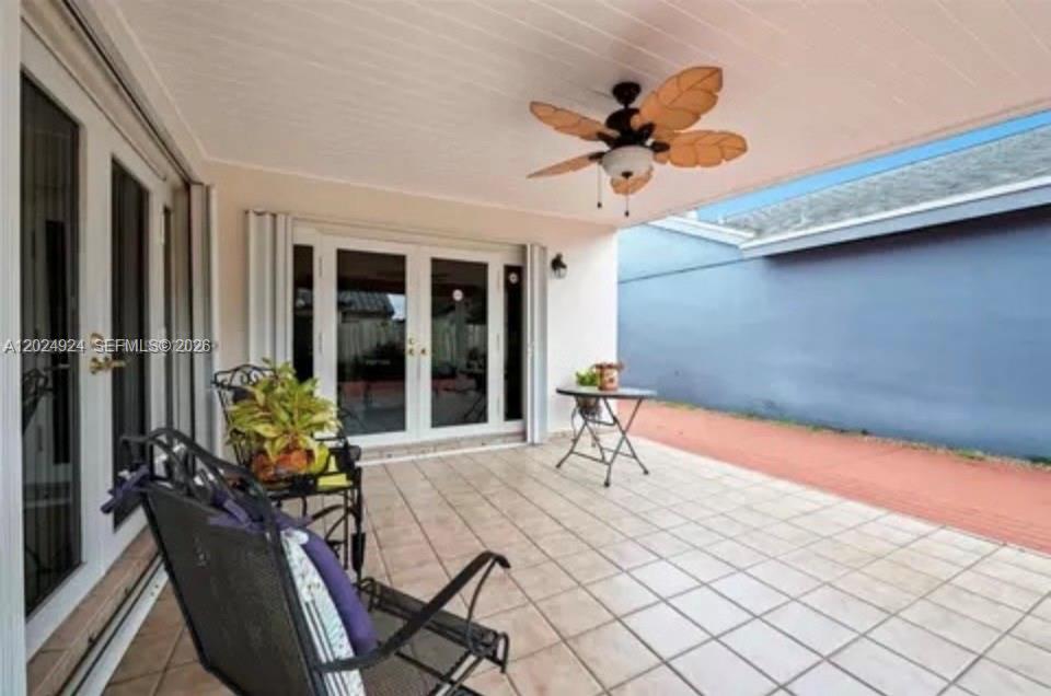 A covered patio features light-colored tile flooring, a ceiling fan, and glass double doors — 13440 SW 28th St, Miami FL 33175, MIAMI, FL