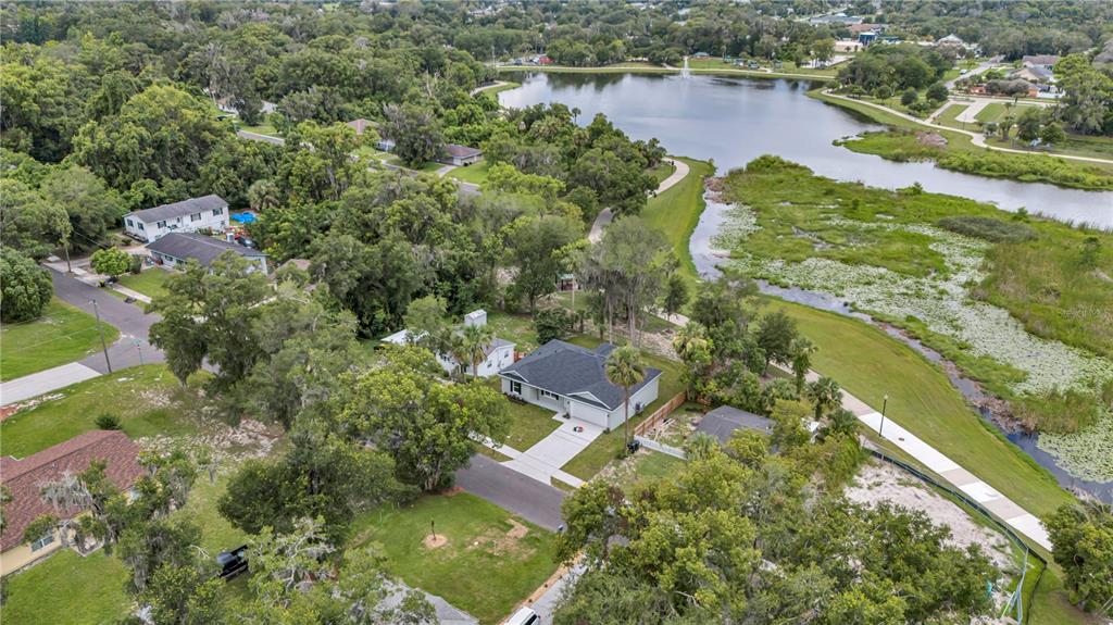 An aerial view shows a house with a dark roof near a lake and trees — 379 S ORANGE AVENUE, ORANGE CITY, FL