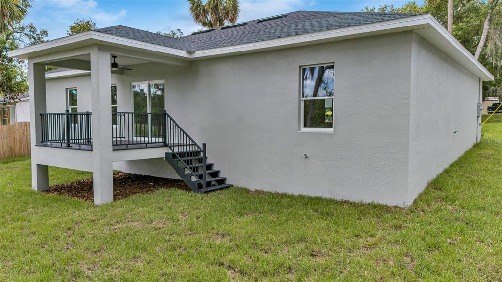 A rear view of a gray house with a raised deck and stairs — 379 S ORANGE AVENUE, ORANGE CITY, FL