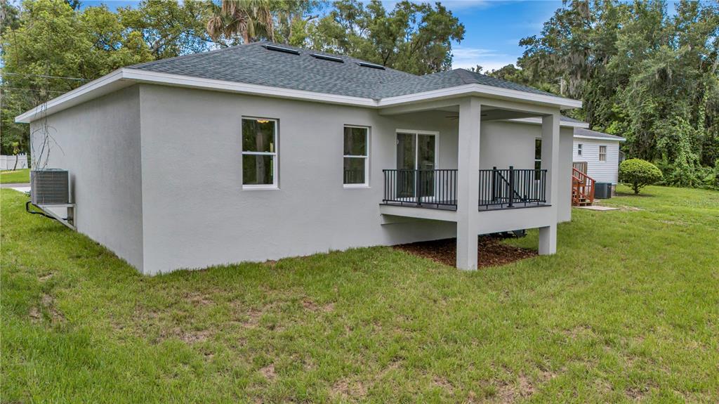 The exterior rear view of a house features a raised deck and a central AC unit — 379 S ORANGE AVENUE, ORANGE CITY, FL