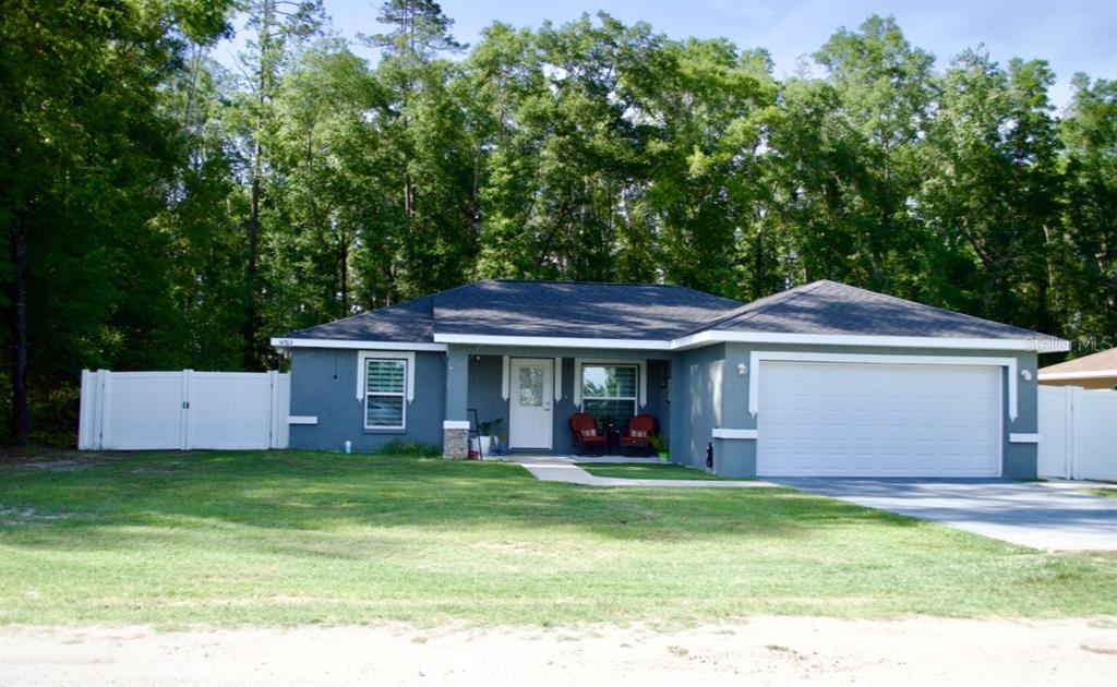 A single-story gray house with a two-car garage and a white vinyl fence — 14763 SW 35TH PLACE, OCALA, FL