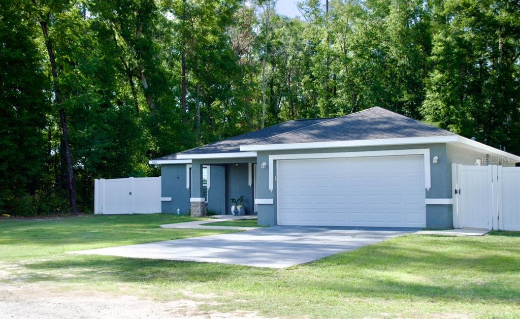 A gray single-story house with a white garage door and a white vinyl fence — 14763 SW 35TH PLACE, OCALA, FL