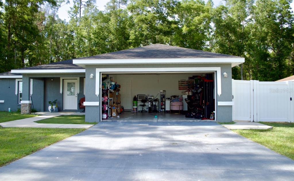 A gray house with a two-car garage, a concrete driveway, and a white privacy fence — 14763 SW 35TH PLACE, OCALA, FL