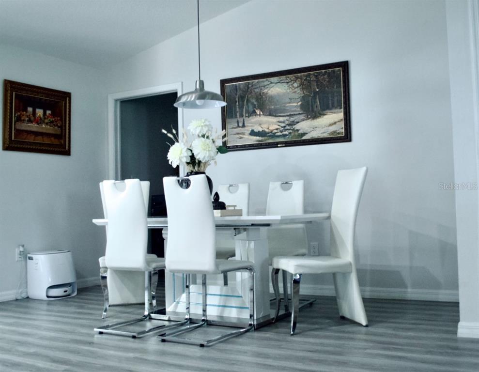 A dining room features a white table with six white chairs and two framed paintings — 14763 SW 35TH PLACE, OCALA, FL