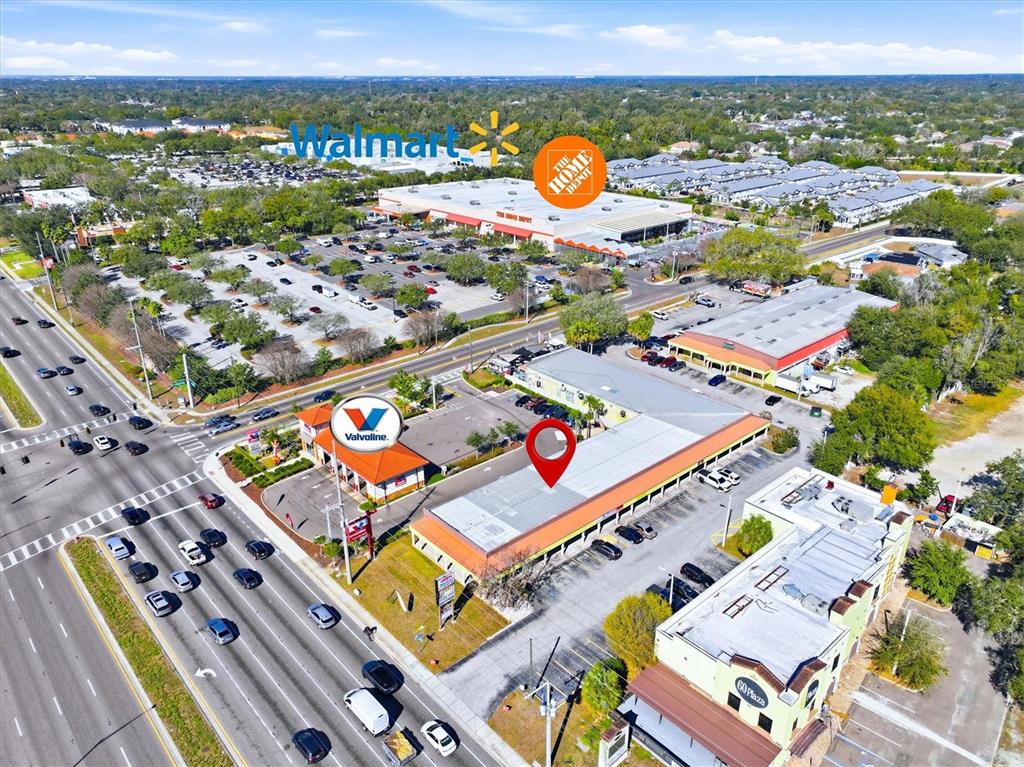 This aerial view shows a commercial plaza with a parking lot and nearby retail stores — 102 PIERCE CHRISTIE DRIVE, VALRICO, FL