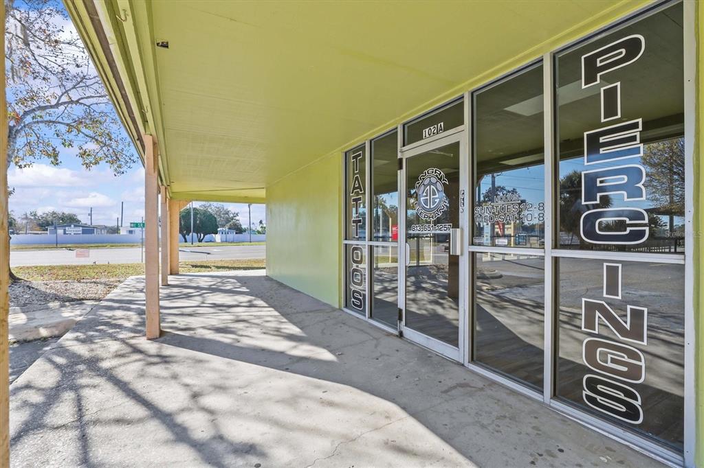 The exterior of a commercial storefront features a covered walkway and glass doors with signage — 102 PIERCE CHRISTIE DRIVE, VALRICO, FL