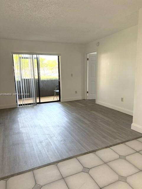 An empty room with light wood-look flooring, white walls, and a sliding glass door — 871 NE 207th Ter # 102, Miami FL 33179, MIAMI, FL