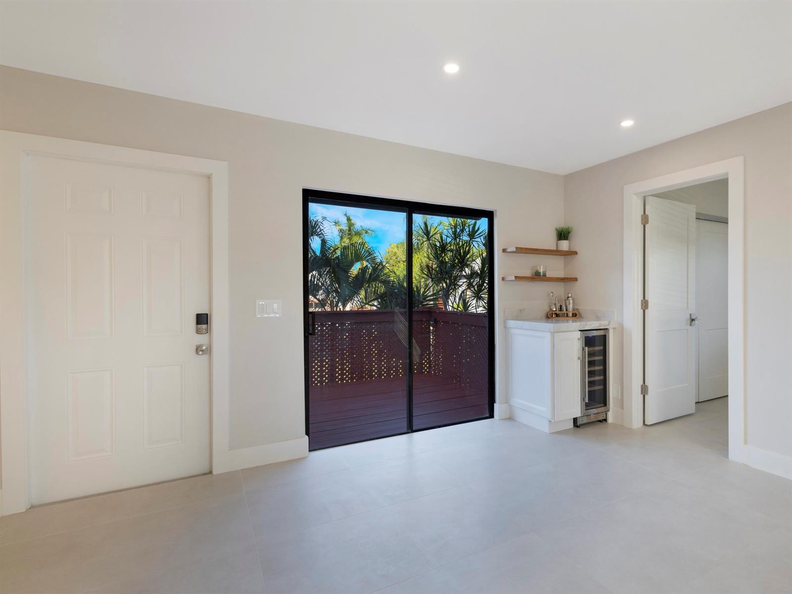 A bright room features light tile floors, a sliding glass door, and a small wet bar — 7 Crossings Circle # H, Boynton Beach FL 33435, BOYNTON BEACH, FL