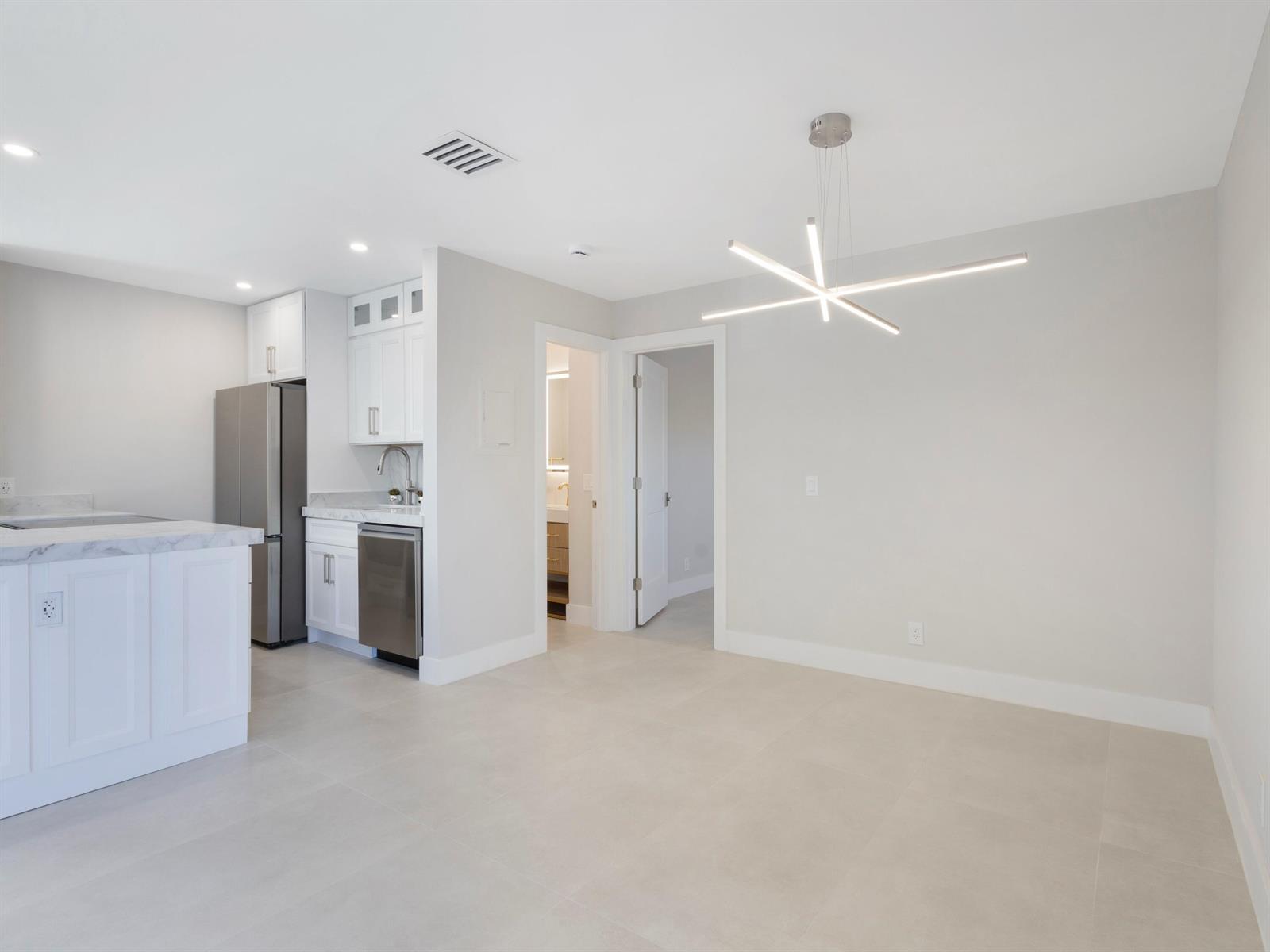 A modern kitchen and dining area feature white cabinetry, stainless steel appliances, and tile flooring — 7 Crossings Circle # H, Boynton Beach FL 33435, BOYNTON BEACH, FL