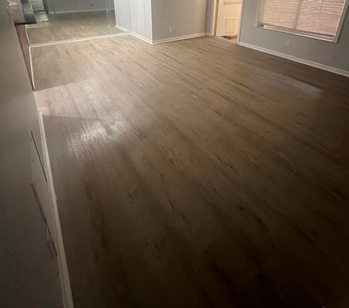 An empty room features gray wood-look plank flooring, light gray walls, and white baseboards — 4815 Sable Pine Circle # C1, West Palm Beach FL 33417, WEST PALM BEACH, FL