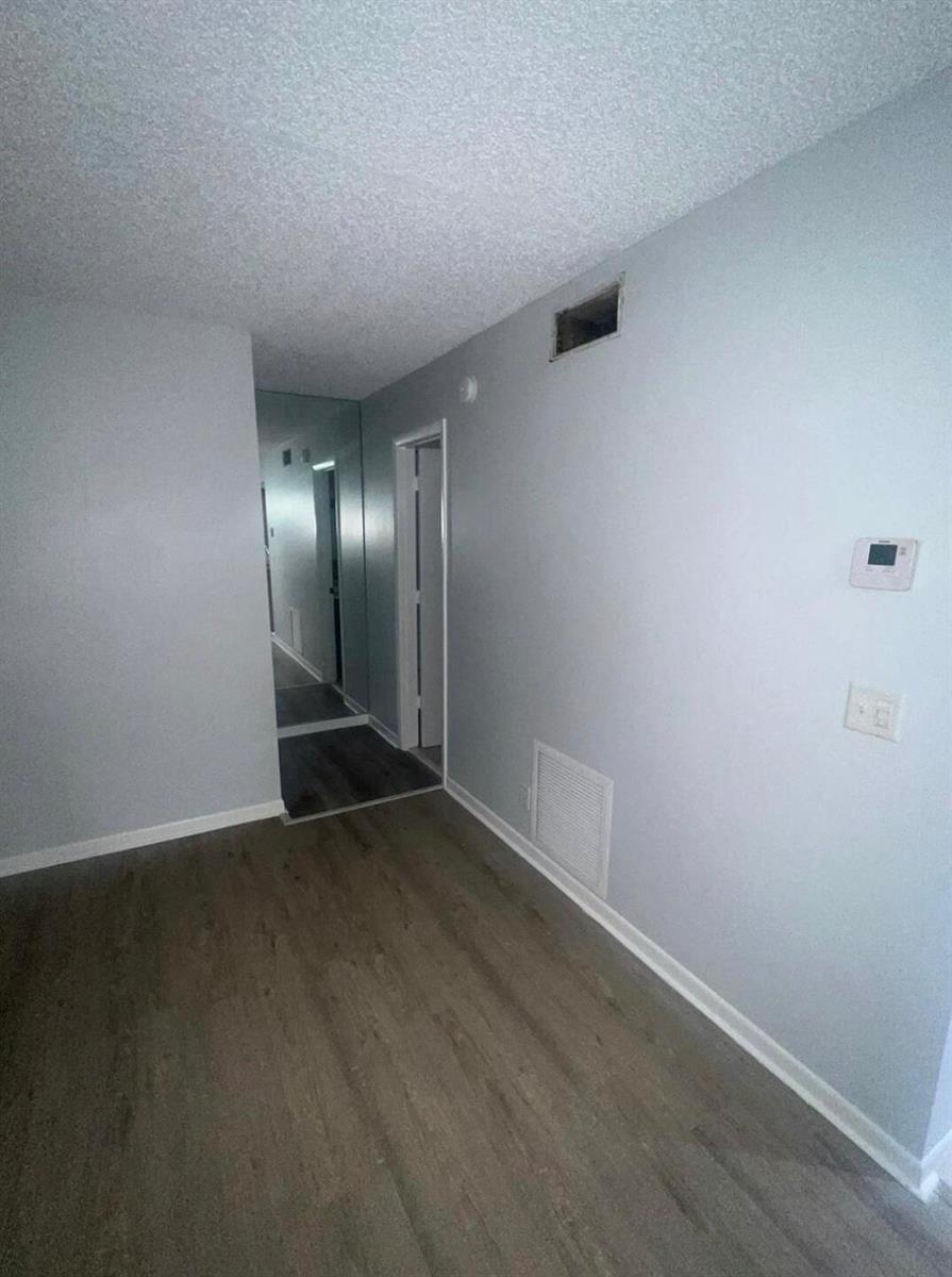 A room with light gray walls, wood-look flooring, a mirrored wall, and a white door — 4815 Sable Pine Circle # C1, West Palm Beach FL 33417, WEST PALM BEACH, FL