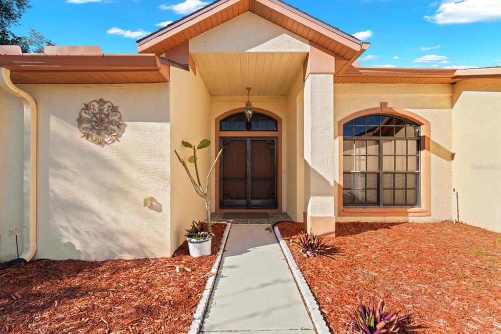 A front view of a house exterior featuring a walkway leading to double entry doors — 9147 DUFFER COURT, HUDSON, FL