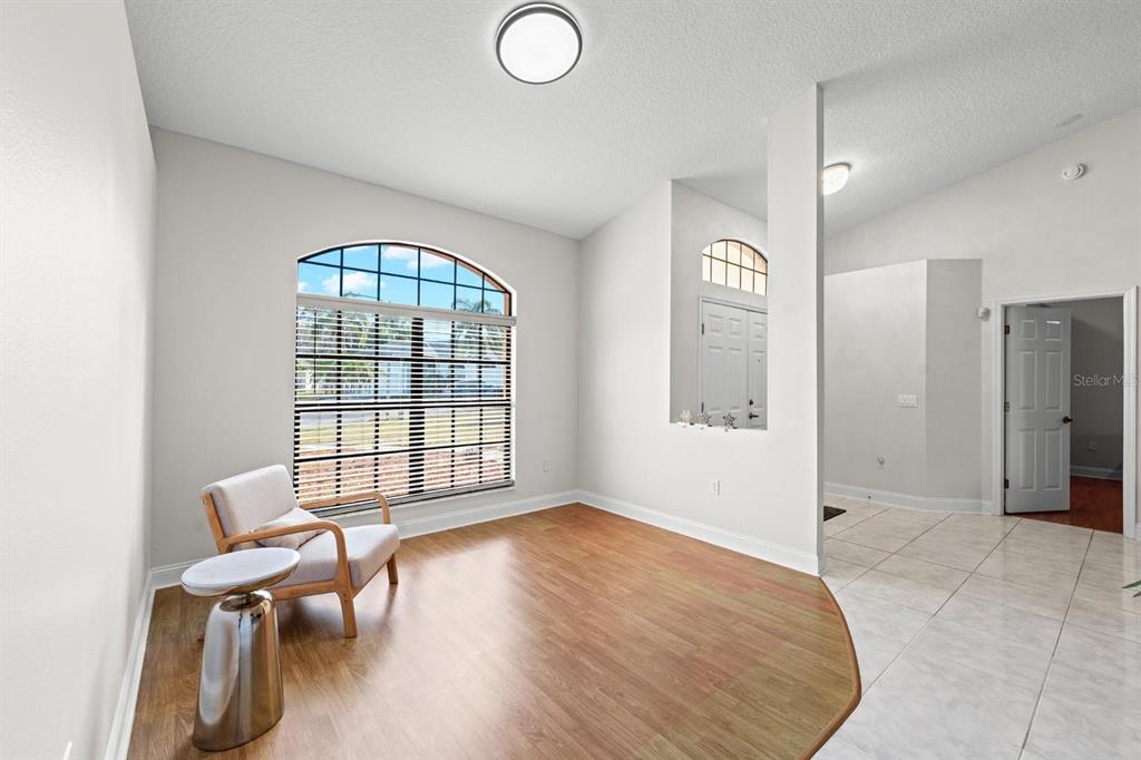 A room with wood-look flooring, a large arched window, and an adjacent tiled entryway — 9147 DUFFER COURT, HUDSON, FL