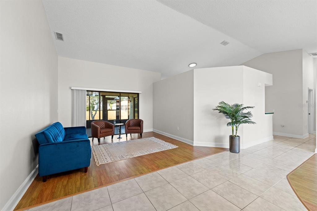 A living room features a blue sofa, two brown chairs, and a mix of tile and wood flooring — 9147 DUFFER COURT, HUDSON, FL