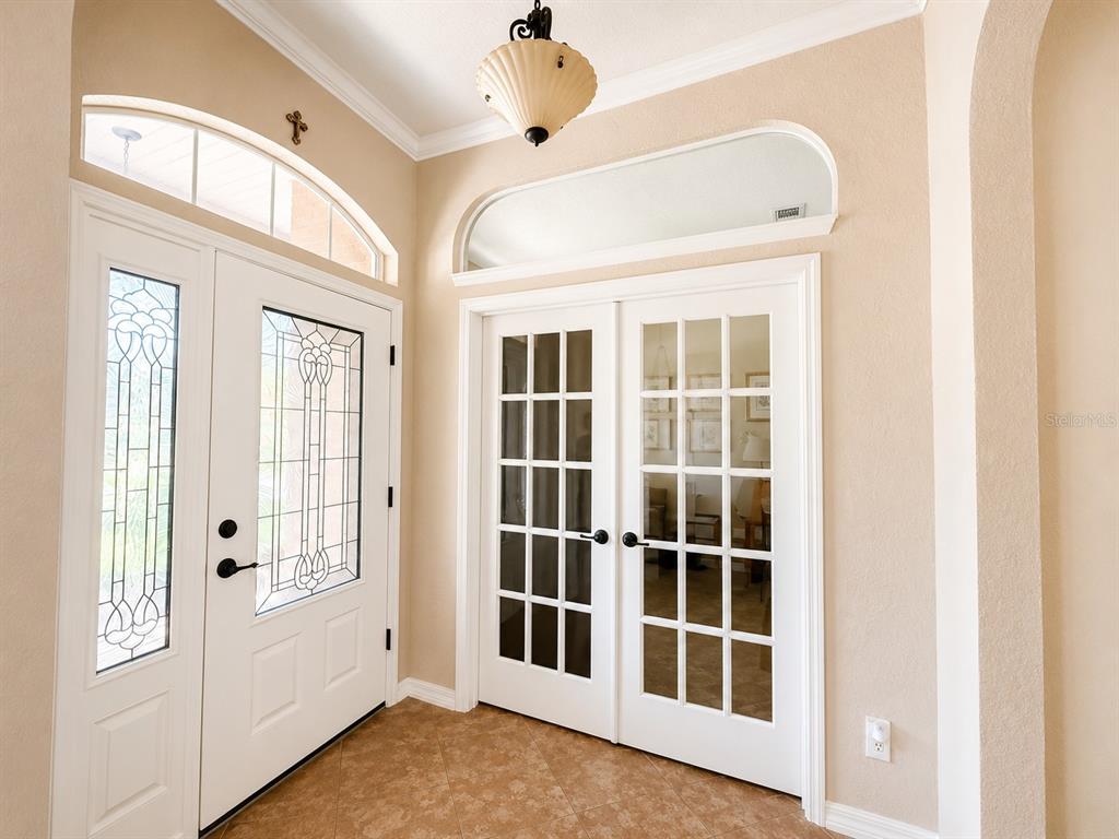 An entryway features a white front door with stained glass, French doors, and tile flooring — 4535 SE 34TH PLACE, OCALA, FL