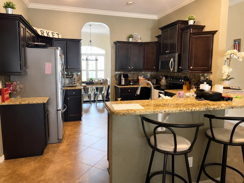 A kitchen features dark wood cabinets, granite countertops, and a breakfast bar with two stools — 4535 SE 34TH PLACE, OCALA, FL