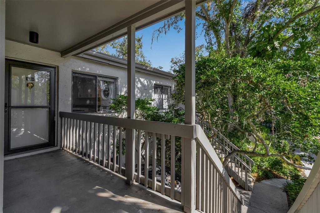 An exterior view of a covered balcony with a railing and stairs leading down — 1508 PELICAN COVE ROAD UNIT 231, SARASOTA, FL