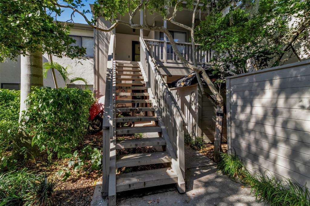 A wooden staircase leads to the elevated entrance of a multi-story residential building — 1508 PELICAN COVE ROAD UNIT 231, SARASOTA, FL