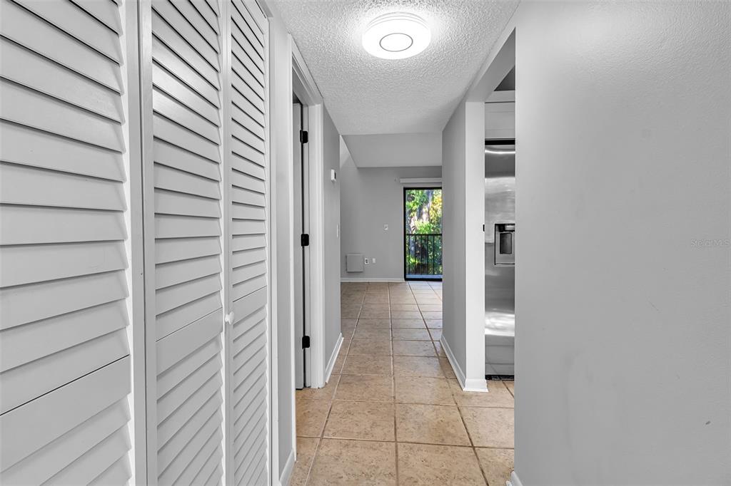 A hallway with tiled floors leads to a room with a glass door and balcony — 1508 PELICAN COVE ROAD UNIT 231, SARASOTA, FL