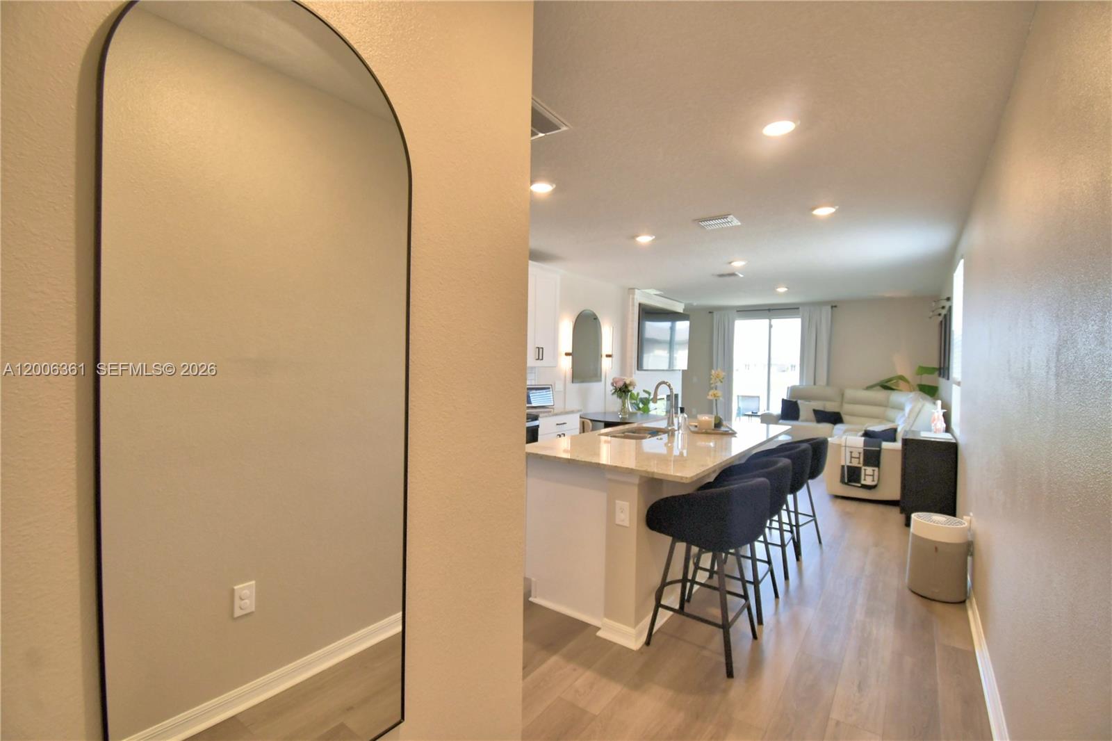 An arched mirror hangs on a wall overlooking an open kitchen and living area — 3563 Broadwing Blvd., Kissimmee FL 34759, KISSIMMEE, FL