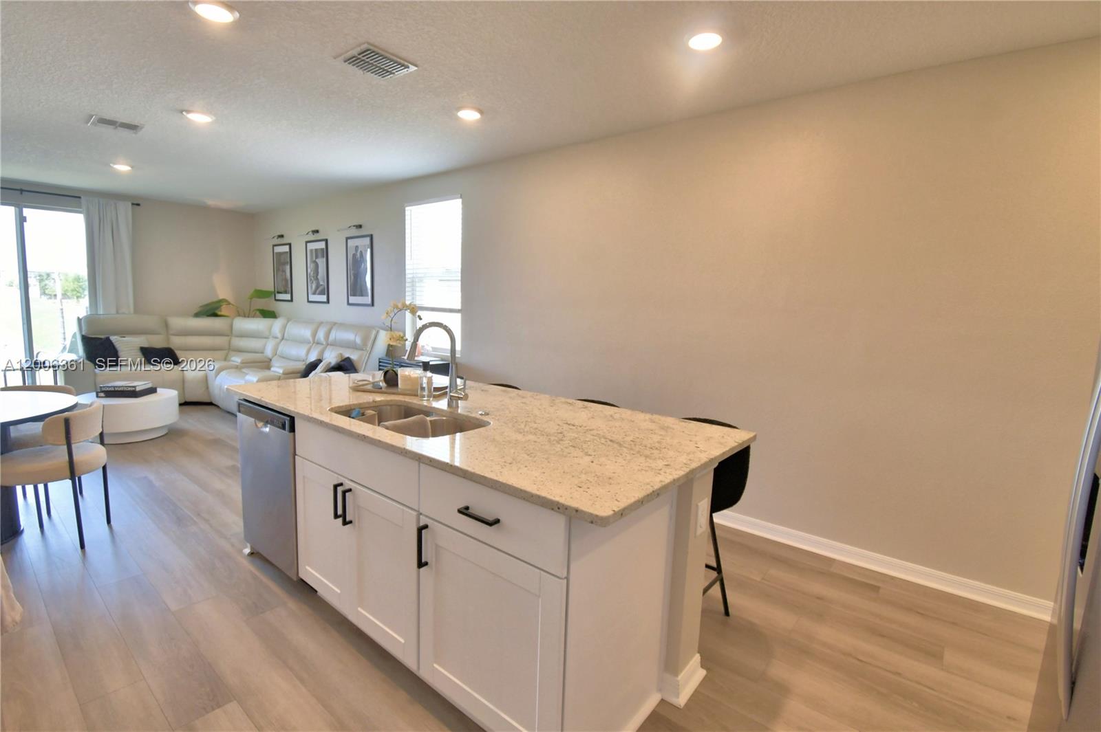A kitchen island with a granite countertop sits in an open-concept living area — 3563 Broadwing Blvd., Kissimmee FL 34759, KISSIMMEE, FL