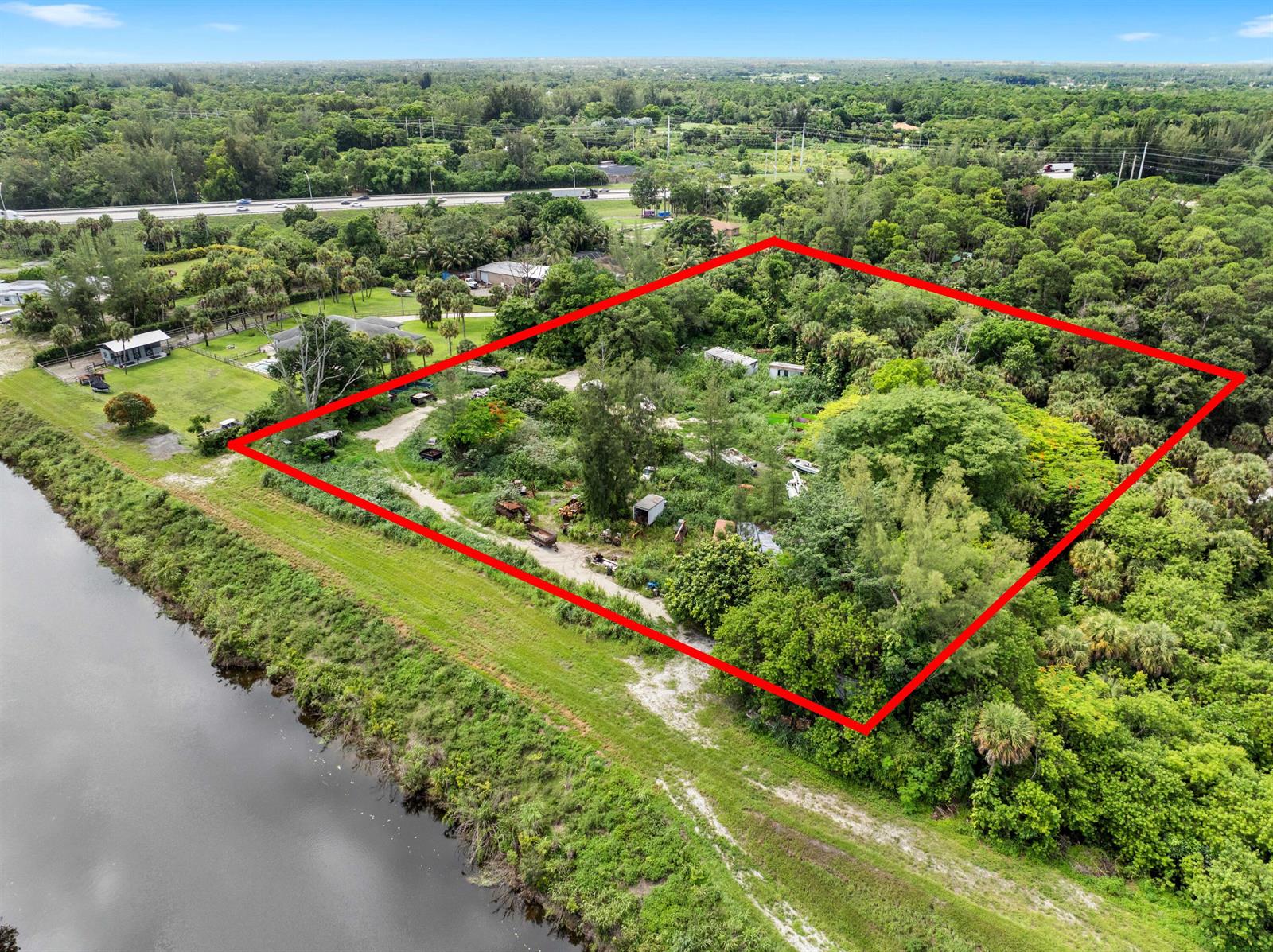 An aerial view shows a rectangular plot of land outlined in red near a canal — 69 Armadillo Way, West Palm Beach FL 33411, WEST PALM BEACH, FL
