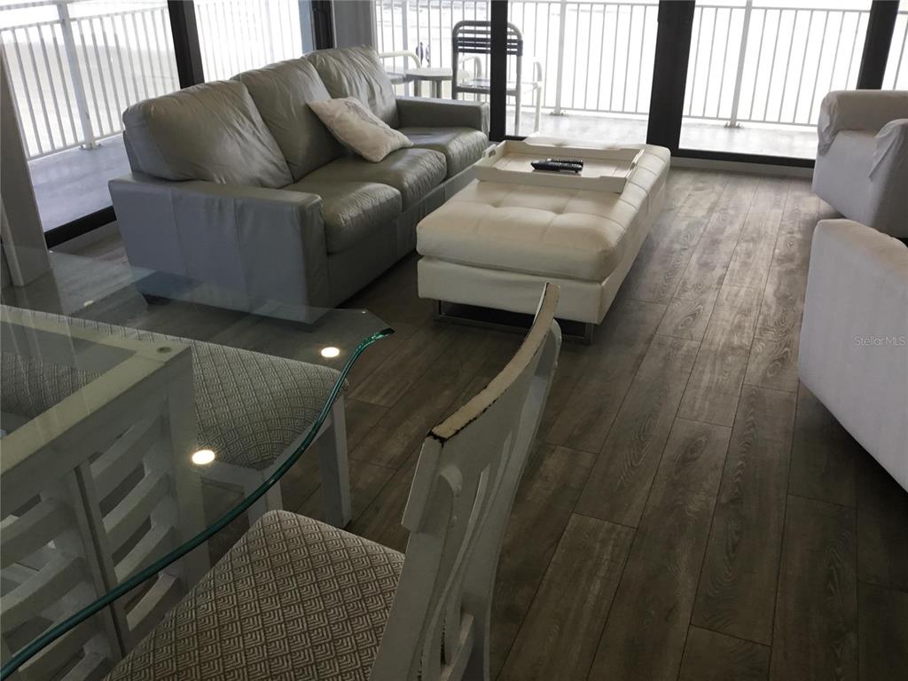 A living room features a gray sofa, white ottoman, and glass-topped dining table — 1571 S ATLANTIC AVENUE UNIT 210, NEW SMYRNA BEACH, FL