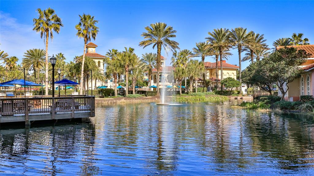 A pond with a central fountain is surrounded by palm trees and Mediterranean-style buildings — 200 OCEAN CREST DRIVE UNIT 524, PALM COAST, FL