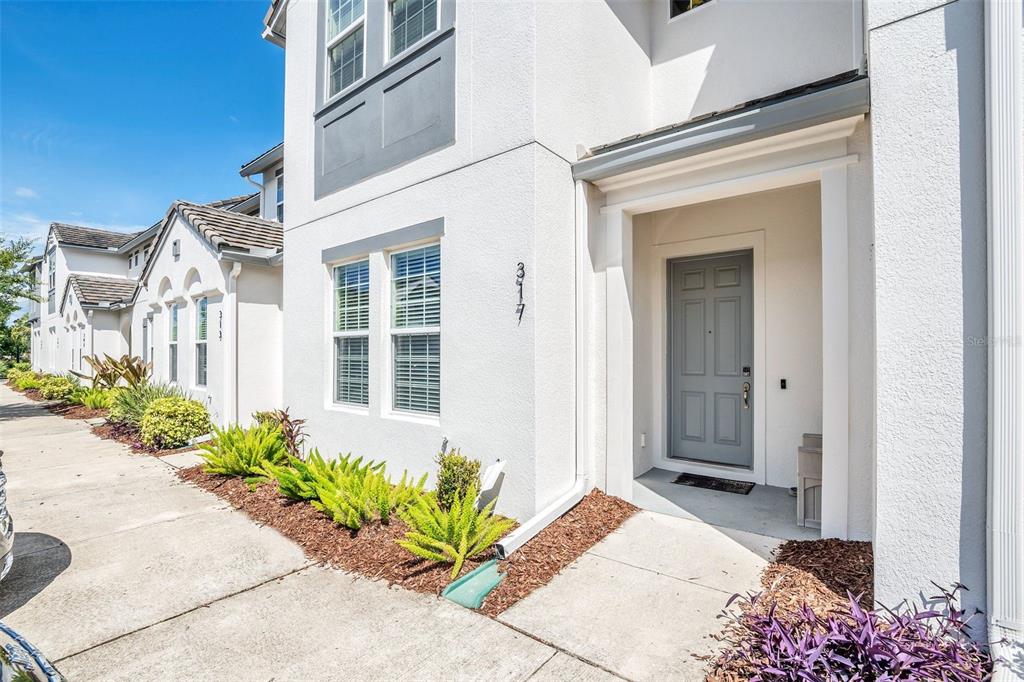 A white two-story townhouse exterior features a gray front door and a concrete walkway — 317 CAPTIVA DRIVE, DAVENPORT, FL