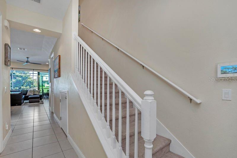 A carpeted staircase with a white railing leads upward next to a tiled hallway — 317 CAPTIVA DRIVE, DAVENPORT, FL