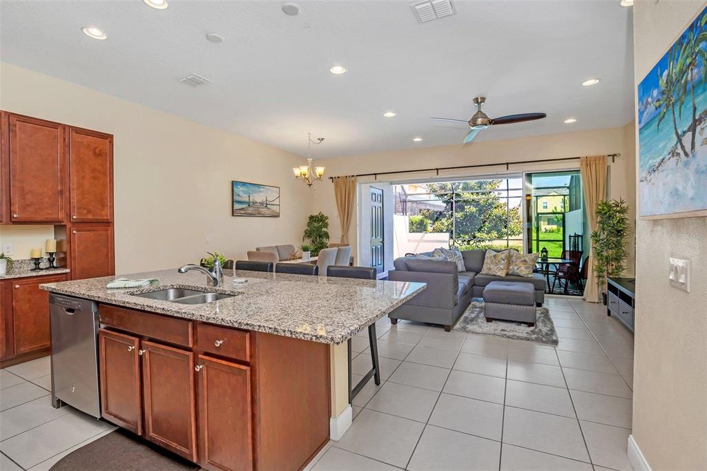 A kitchen with a granite island overlooks a living room with tile floors and sliding doors — 317 CAPTIVA DRIVE, DAVENPORT, FL