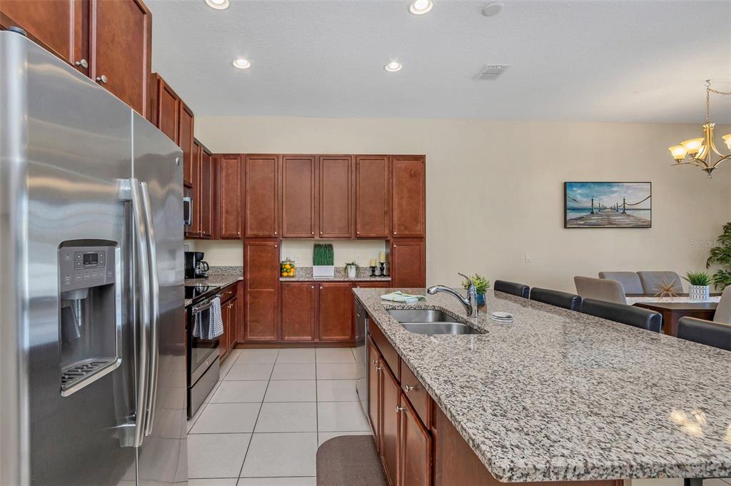 A kitchen features wood cabinets, granite countertops, a large island with a sink, and appliances — 317 CAPTIVA DRIVE, DAVENPORT, FL