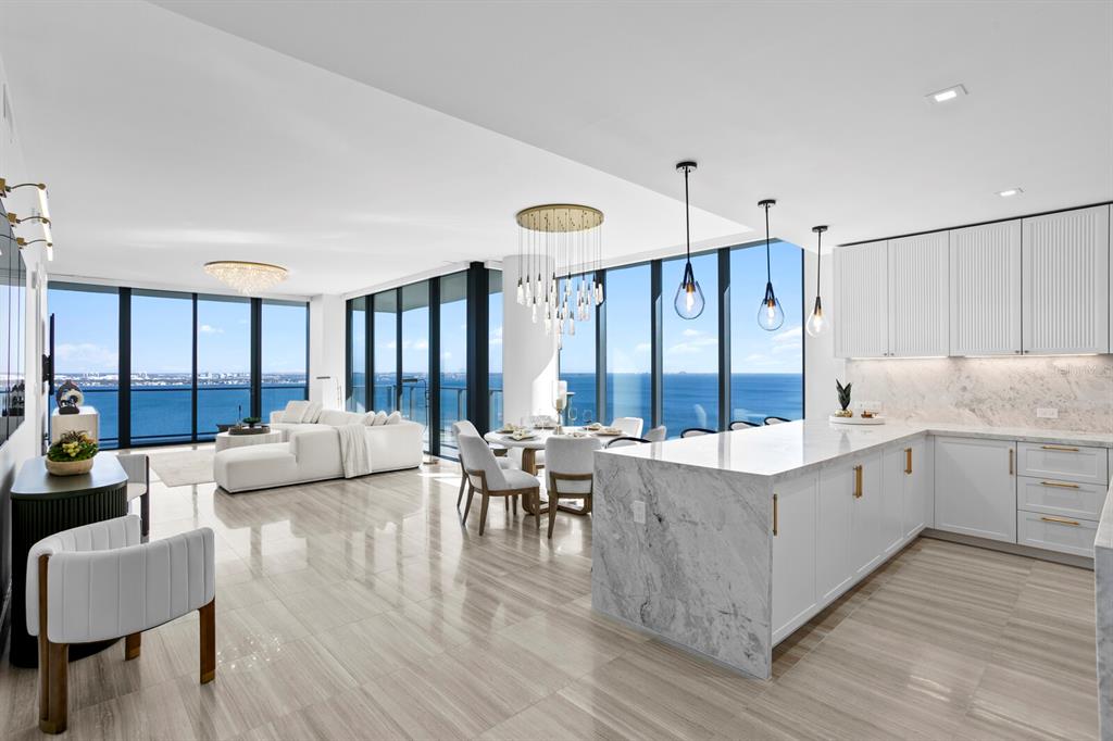 An open-concept kitchen and living area features marble countertops, white cabinetry, and floor-to-ceiling windows — 3101 BAYSHORE BOULEVARD UNIT 1804, TAMPA, FL