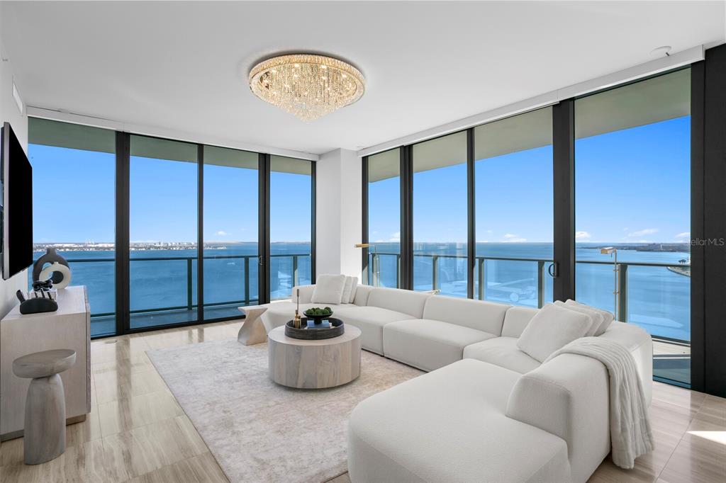 A modern living room features a white sectional sofa, a round coffee table, and floor-to-ceiling windows — 3101 BAYSHORE BOULEVARD UNIT 1804, TAMPA, FL