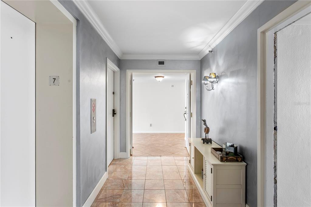 A tiled hallway leads to an open doorway, featuring gray walls and a console table — 3301 BAYSHORE BOULEVARD UNIT 702E, TAMPA, FL