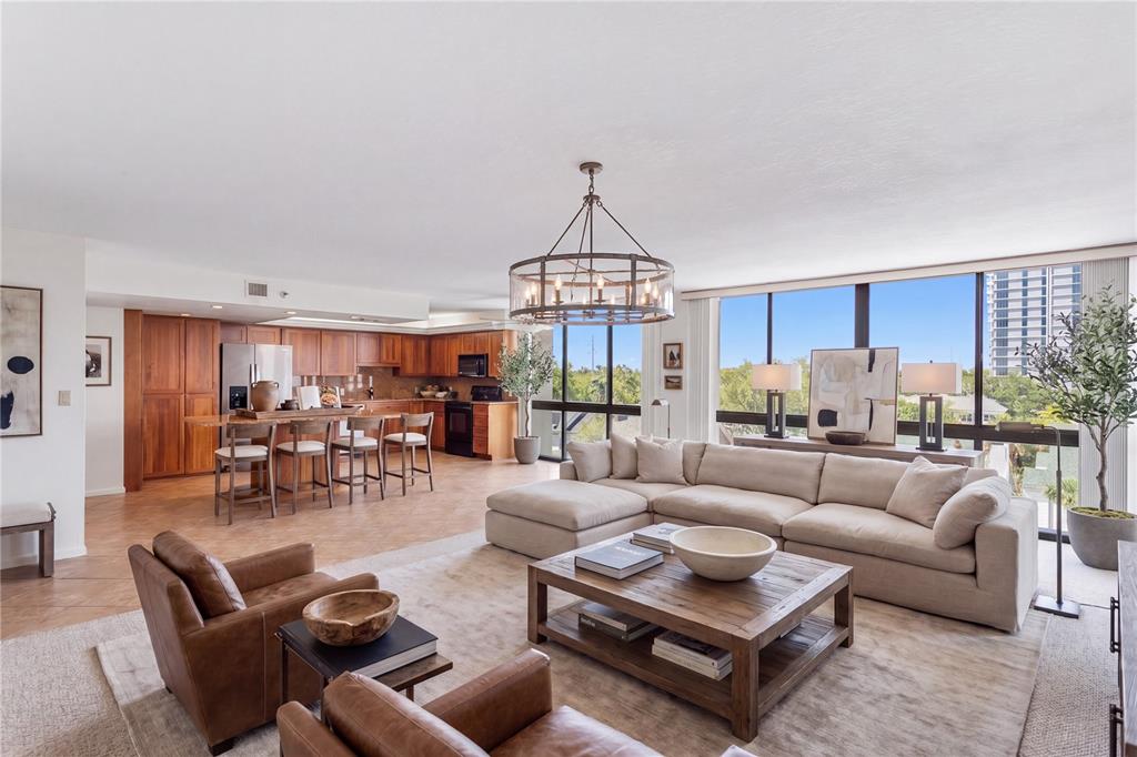 An open-concept living room and kitchen featuring wood cabinetry, leather armchairs, and floor-to-ceiling windows — 3301 BAYSHORE BOULEVARD UNIT 702E, TAMPA, FL