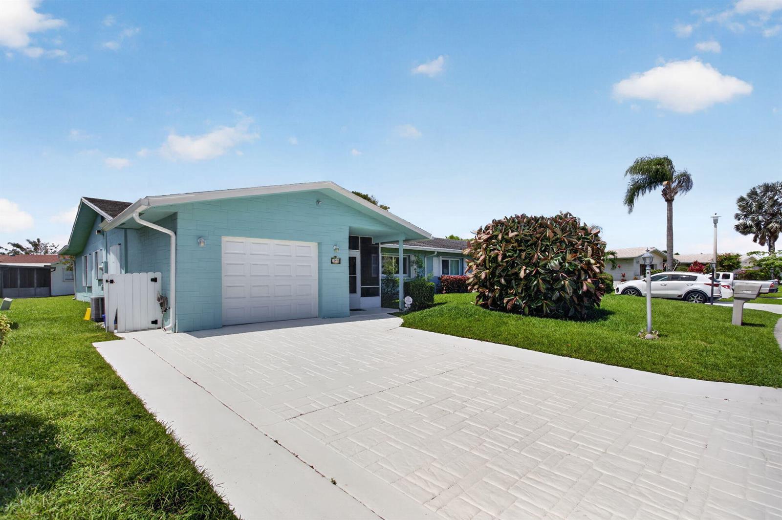 A light blue single-story house features a white garage door and a paved driveway — 13891 Packard Terrace, Delray Beach FL 33484, DELRAY BEACH, FL
