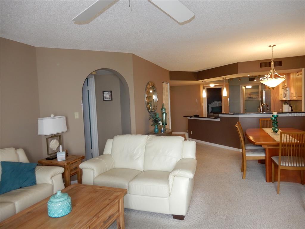 A living room with beige walls, white leather furniture, and an adjacent dining area — 5151 ISLA KEY BOULEVARD S UNIT 324, ST PETERSBURG, FL