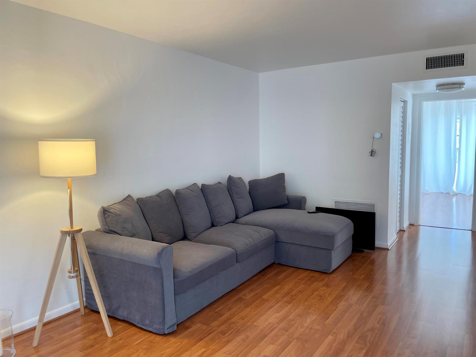 A living room features a gray sectional sofa, a tripod floor lamp, and wood flooring — 2920 Cynthia Lane # 203, FL 33461, FL