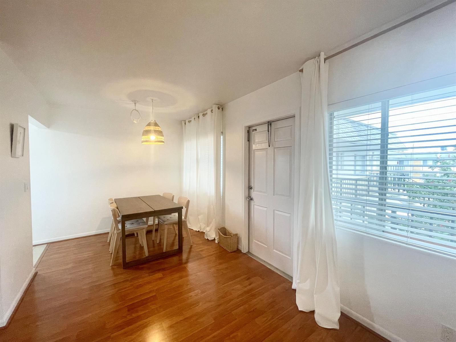 A dining area features hardwood floors, a wooden table with four chairs, and white curtains — 2920 Cynthia Lane # 203, FL 33461, FL