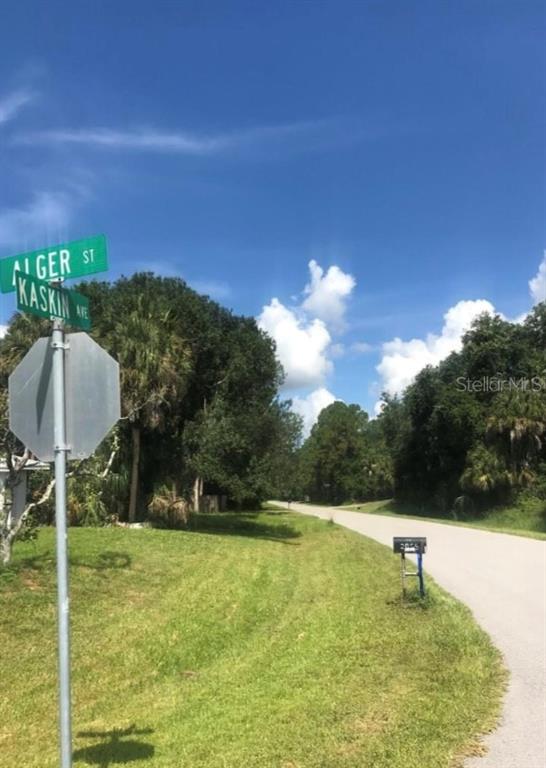 A street sign for Alger Street and Kaskin Avenue stands beside a rural paved road — 0966054925 KASKIN AVENUE, NORTH PORT, FL
