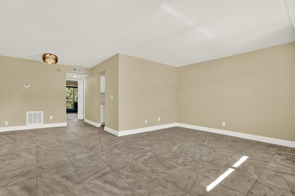 An empty room with beige walls, large gray tile flooring, and a ceiling light fixture — 9125 TUDOR DRIVE UNIT D109, TAMPA, FL