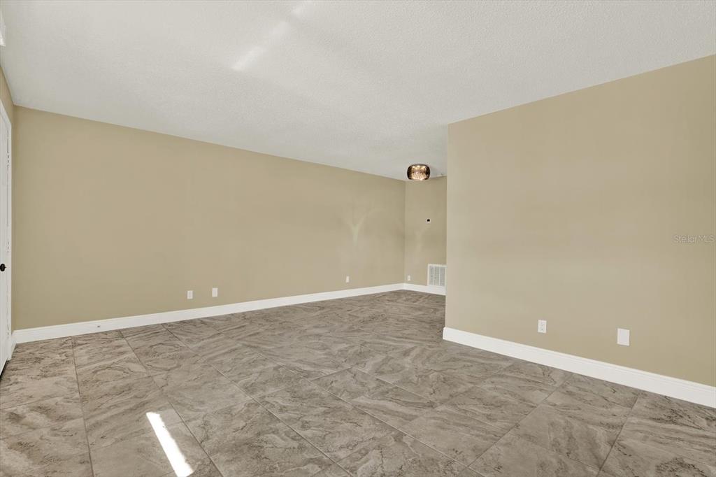 An empty room features beige walls, white trim, and large gray marble-patterned floor tiles — 9125 TUDOR DRIVE UNIT D109, TAMPA, FL
