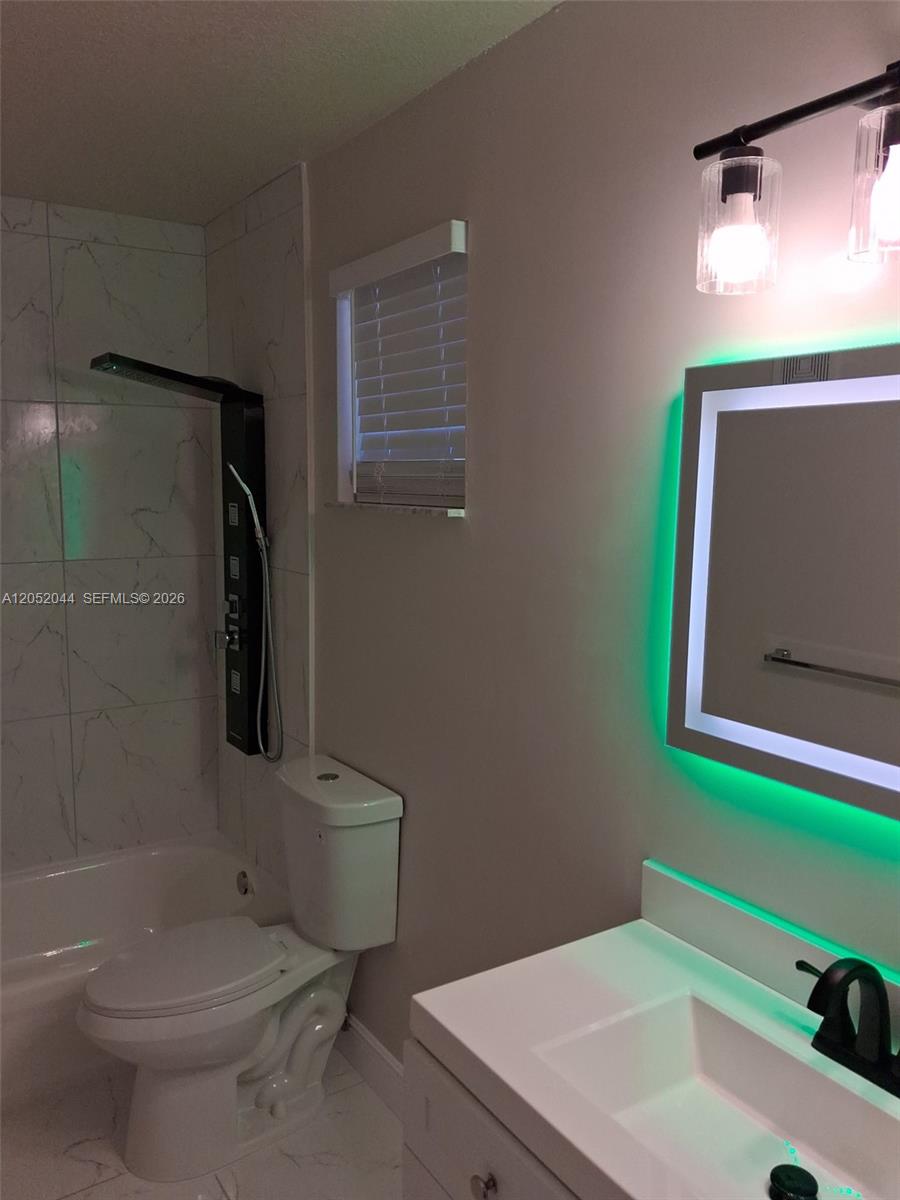 A bathroom features a white vanity, a toilet, and a shower with marble-patterned tile walls — 7245 NW 173rd Dr # 2502, Hialeah FL 33015, HIALEAH, FL